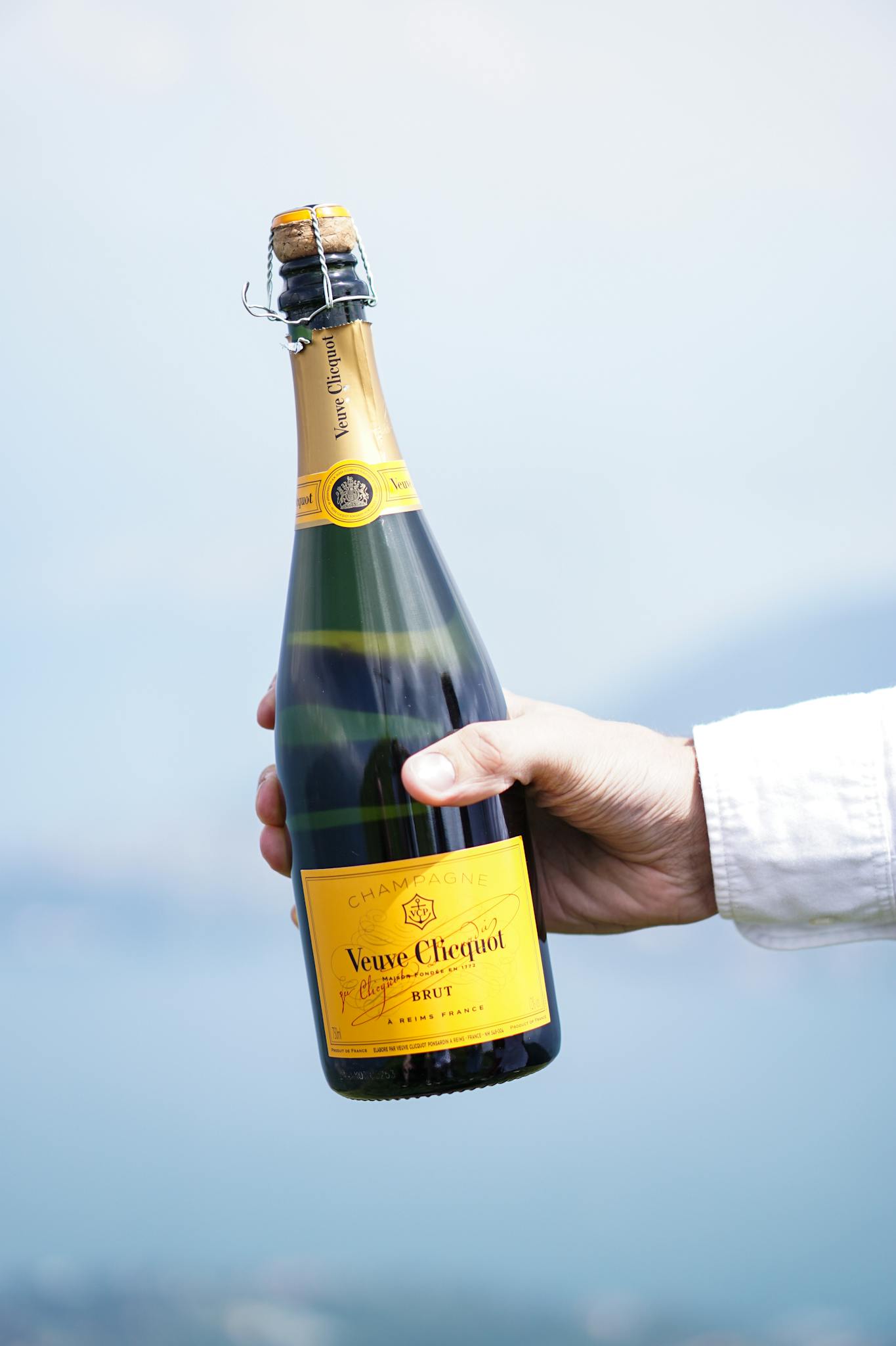 A hand holding a Veuve Clicquot champagne bottle in Lombardy, Italy, perfect for celebrations.