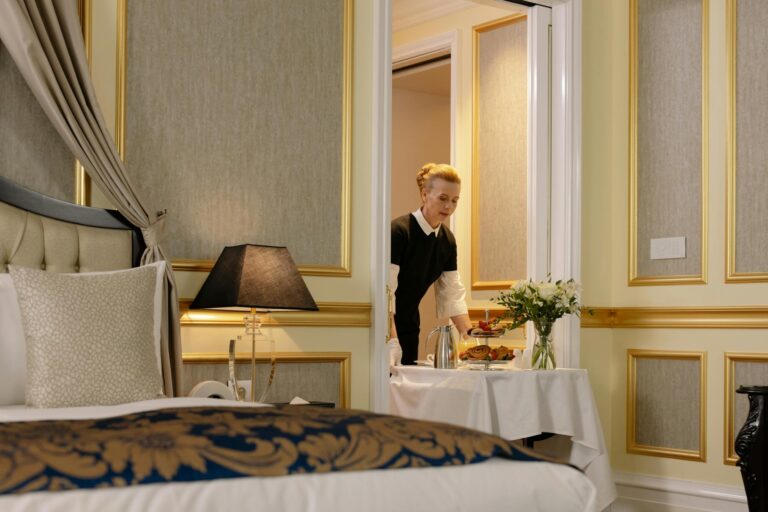 A hotel employee delivers elegant room service with a tray of breakfast in a luxurious hotel setting.